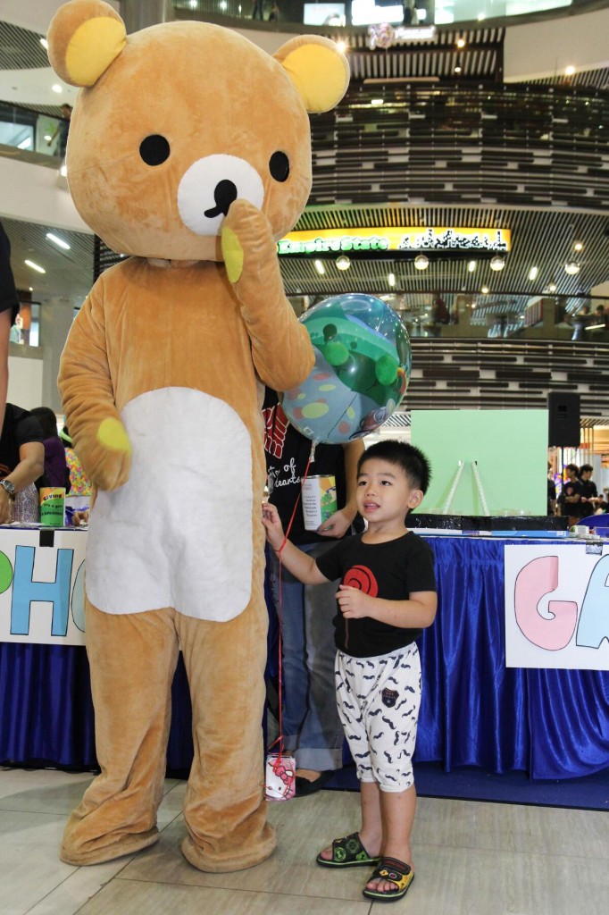 PLUSH TOY: Event mascot Rilakkuma entertaining a young boy.