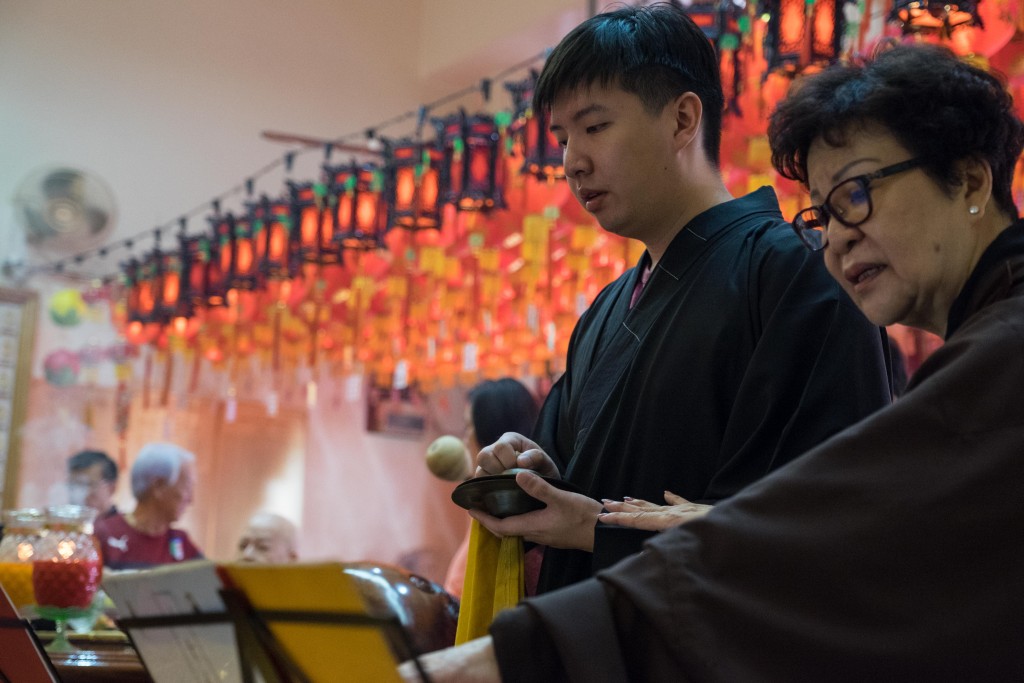 Under the guidance of senior devotees, Chong plays the cymbal during a prayer session.